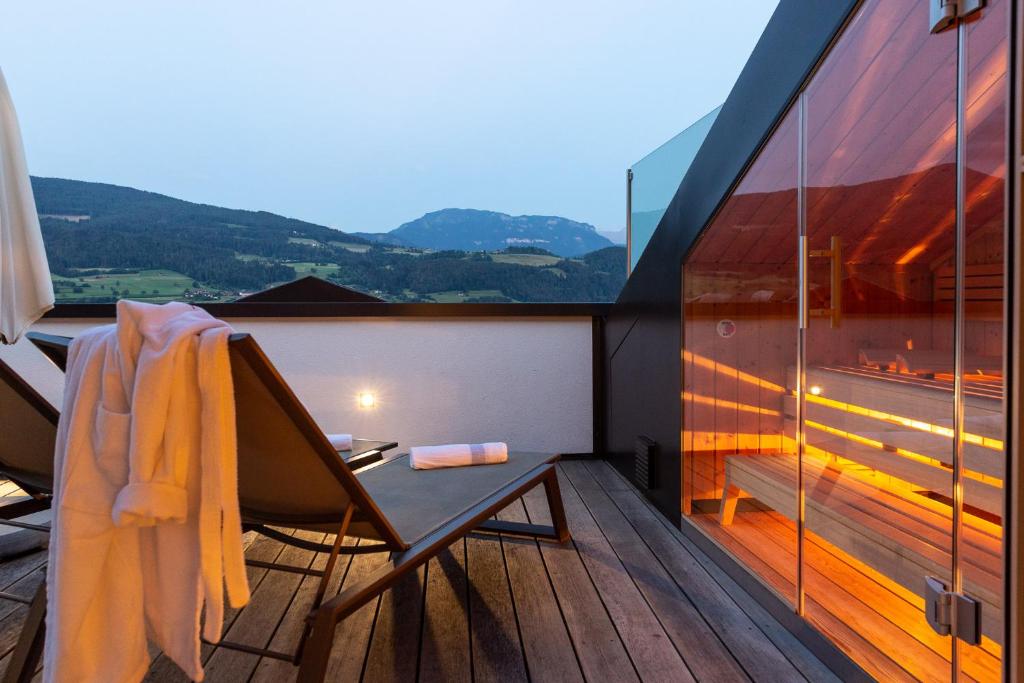 einen Balkon eines Hauses mit einem Tisch und einem Fenster in der Unterkunft Granpanorama Hotel StephansHof in Villanders