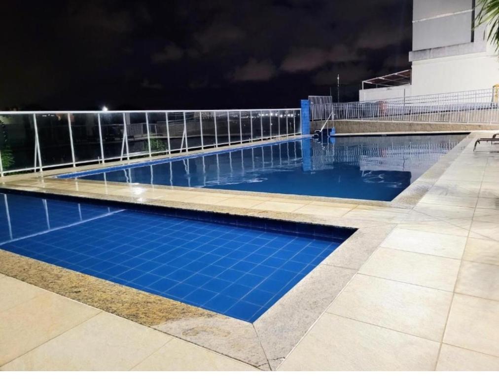 uma piscina à noite com água azul em Residencial Jardim da Costa com 2 quartos a 4 km praia em João Pessoa