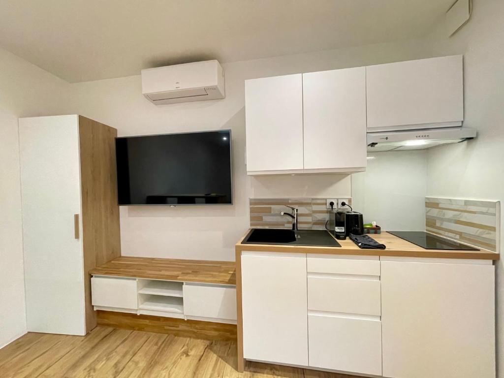 uma cozinha com armários brancos e uma televisão de ecrã plano em Studio Toulouse Pargaminières em Toulouse