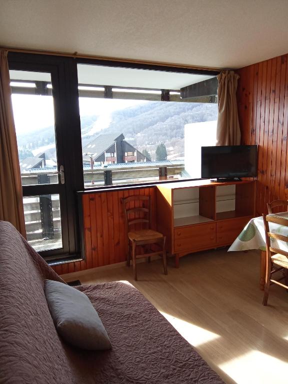 - une chambre avec un lit et un bureau avec une grande fenêtre dans l'établissement Appartement plein cœur Super-Besse, à Besse-et-Saint-Anastaise