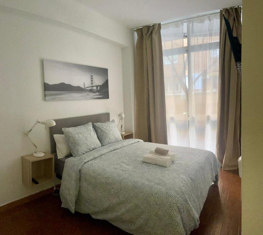 a bedroom with a bed with a large window at Rooms Cáceres in Madrid