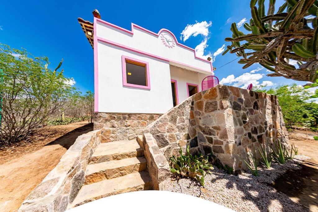 un pequeño edificio rosa y blanco con escaleras delante en Casa Beija-flor - Ilha do Ferro en Pão de Açúcar