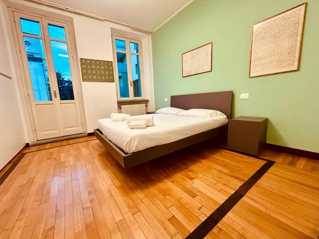 ein Schlafzimmer mit einem Bett in einem Zimmer mit Holzböden in der Unterkunft Kibilù - Via Medaglie D'Oro Centro Città con Parcheggio in Varese