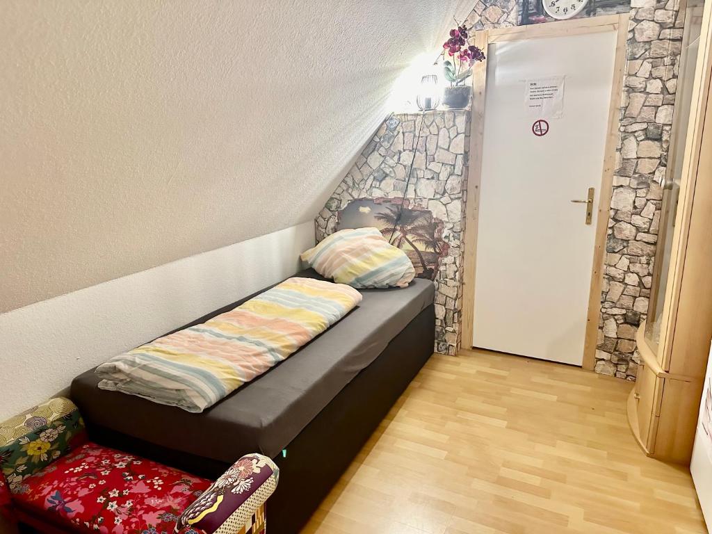 a small bed in a room with a rock wall at Ferienzimmer Healing und Montuerwohnung in Weißenfels