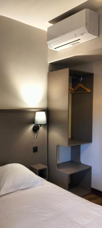 a bedroom with a bed and a light on a wall at HÔTEL ROYAL MONTREUIL in Montreuil
