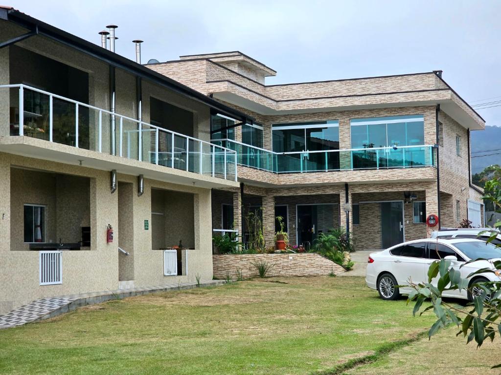 a house with a car parked in front of it at Cantinho da Amizade in Ubatuba