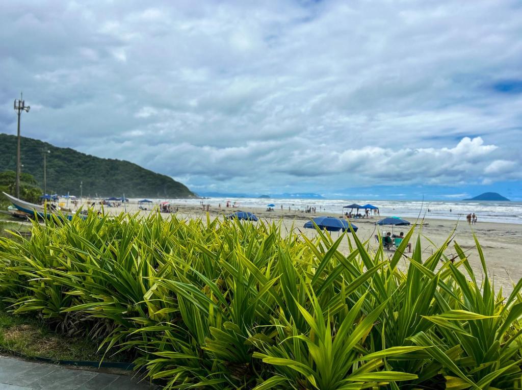 a beach with people and umbrellas and the ocean at Incrivel flat a beira mar na Praia de Guaratuba SP in Praia Guaratuba