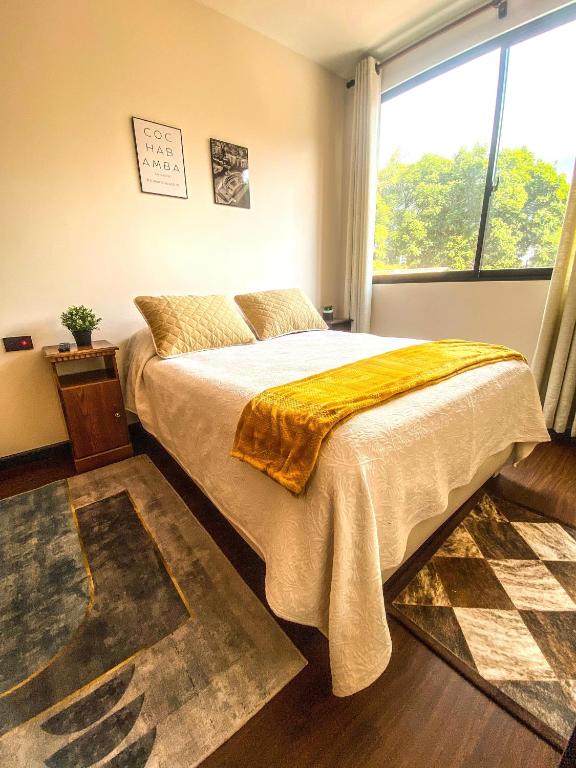 een slaapkamer met een bed en een groot raam bij Acogedor departamento céntrico in Cochabamba
