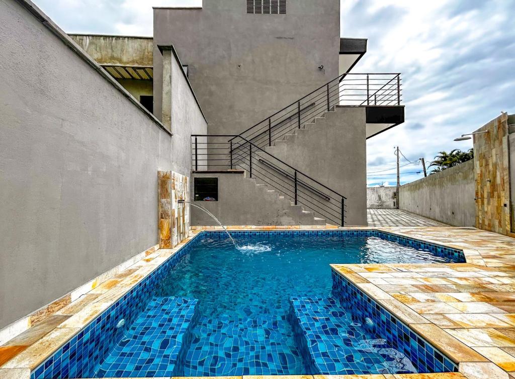 a house with a swimming pool in front of a building at Otimo flat a beira mar na Praia de Guaratuba SP in Bertioga