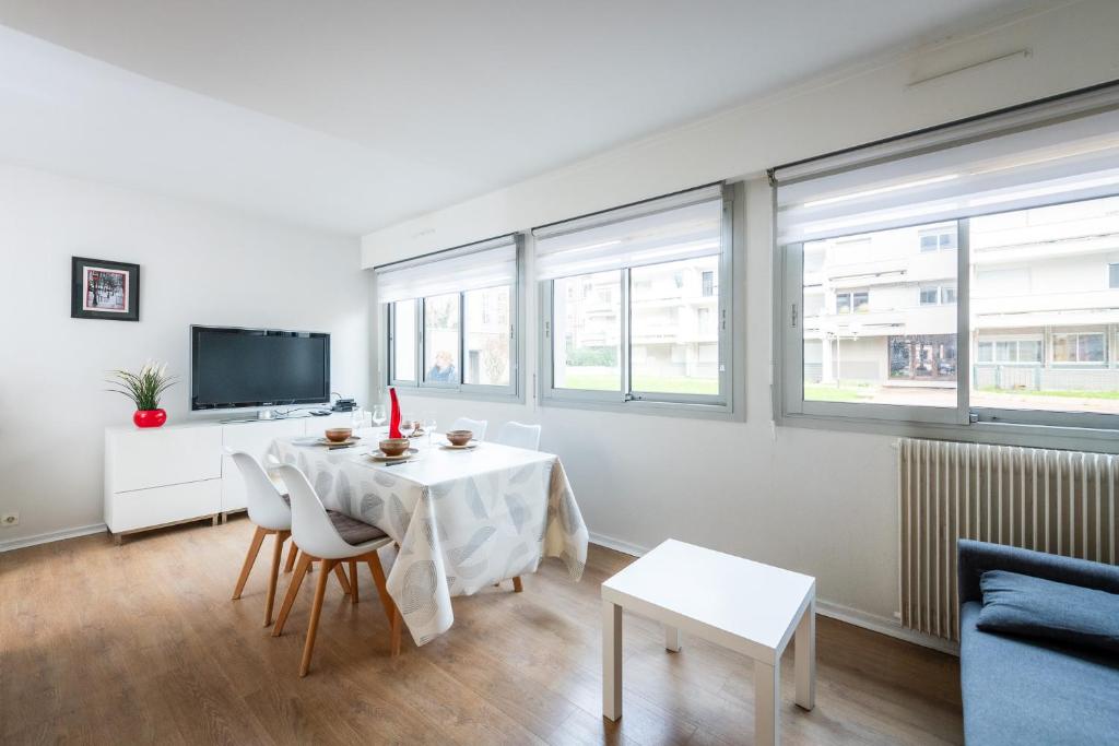 - un salon avec une table, des chaises et une télévision dans l'établissement Aux Jardins de l'Hôtel de ville - Appartement Hypercentre avec Parking Privé, à Rouen