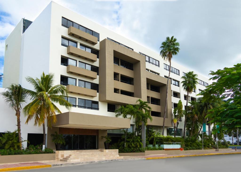 a building with palm trees in front of it at Smart Cancun the Urban Oasis in Cancún