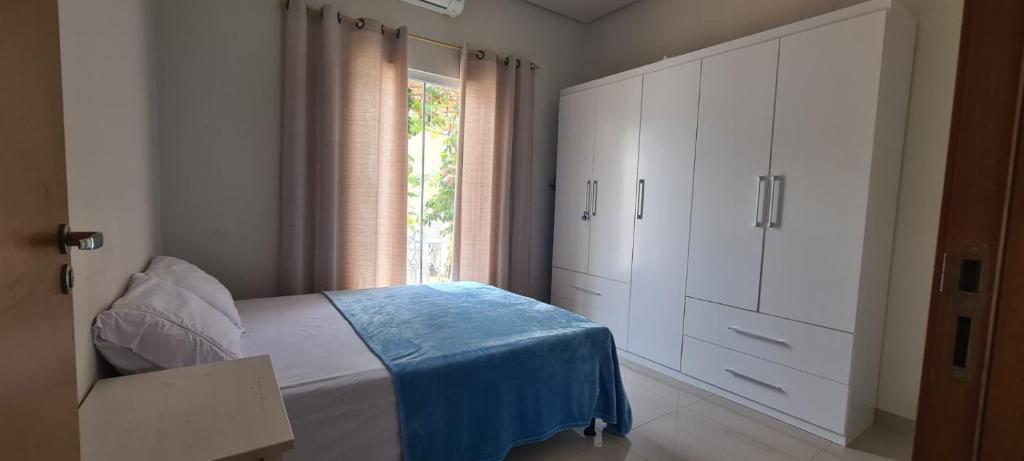 um quarto com uma cama com armários brancos e uma janela em Palmas home rental em Palmas