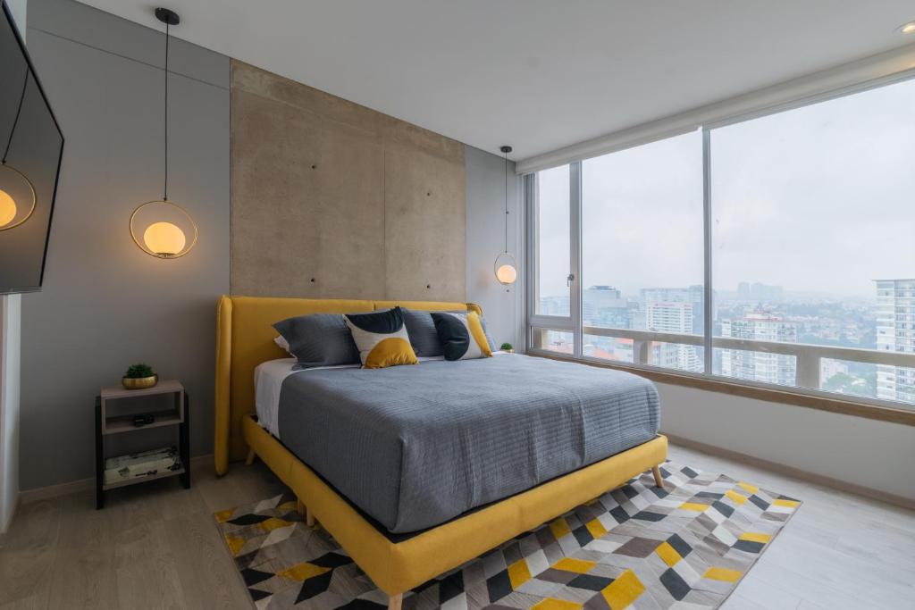 a bedroom with a yellow bed and large windows at Beautiful Apt in Santa Fe with Panoramic Views! in Mexico City