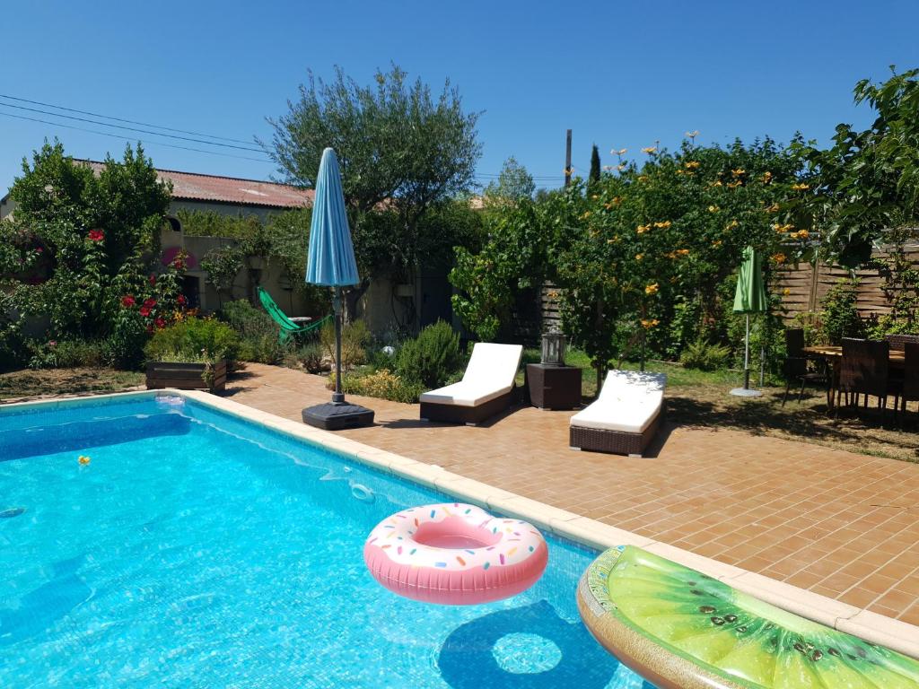 - une piscine avec une chaise de plage et un parasol dans l'établissement Paradis au soleil, à Alignan-du-Vent