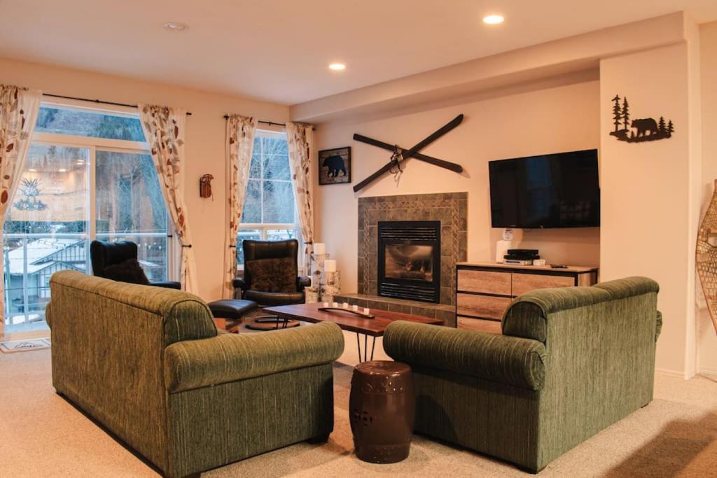 a living room with two couches and a fireplace at Burfield Lodge, Ski In Ski Out with Hot Tub in Sun Peaks