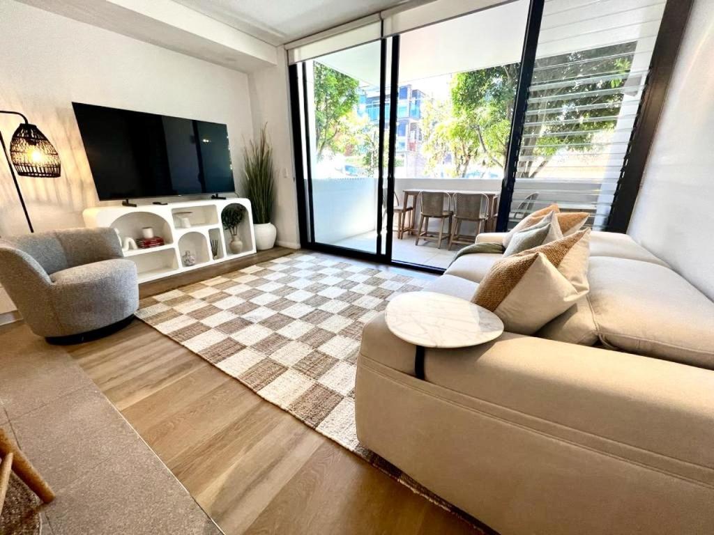 a living room with a couch and a television at Luxury 1 BR Apartment in Randwick- Walk to hospital UNSW Dining W parking and lift and AC in Sydney
