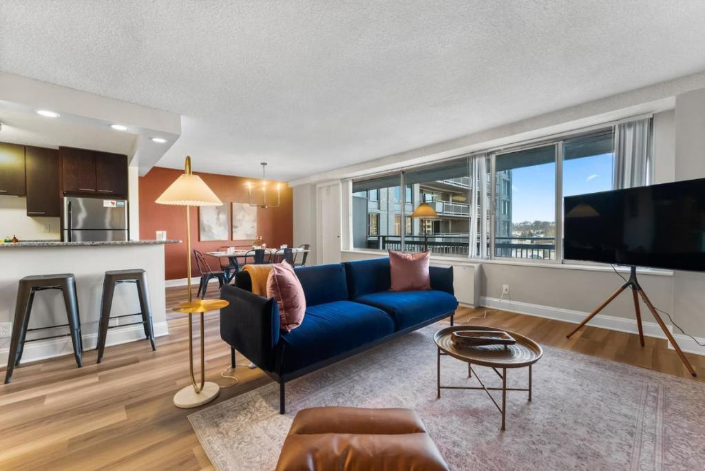 a living room with a blue couch and a kitchen at Chic DC Getaway Near Metro in Arlington