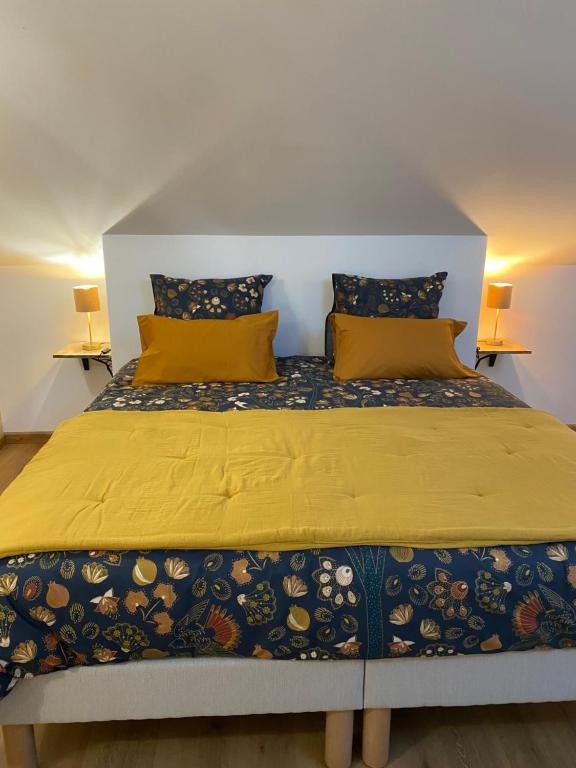 una camera da letto con un grande letto con lenzuola e cuscini gialli di Le Lys Ecossais a Aubigny-sur-Nère