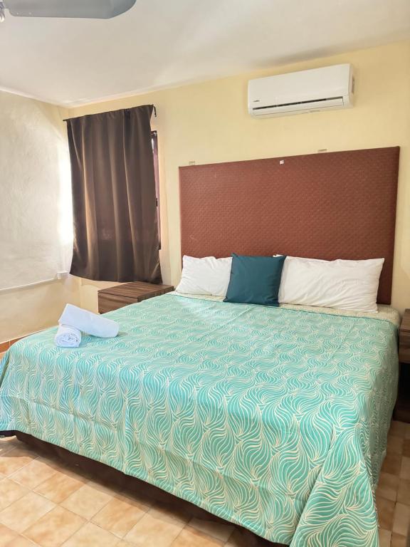 um quarto com uma cama grande e um edredão verde em La Casita de Jonas em Puerto Morelos