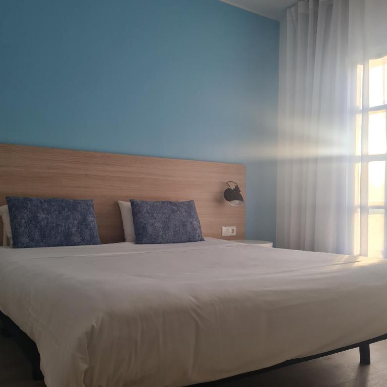 a bedroom with a large white bed with blue pillows at Flag Hotel Santarém in Pernes