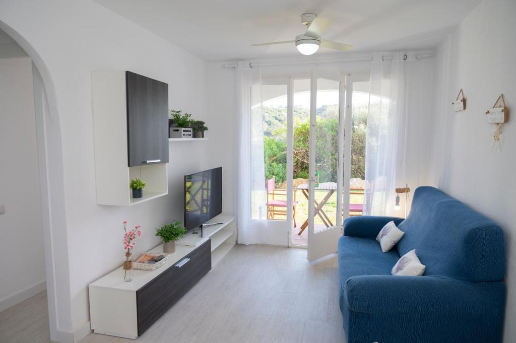 uma sala de estar com um sofá azul e uma televisão em Apartamento Sol Isla Arenal de'n Castell em Arenal d'en Castell