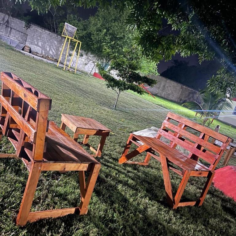 two wooden benches and a picnic table in the grass at Villa Hermanos Luciano 