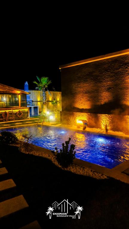 a swimming pool in front of a building at night at Şile SHAMAN BUNGALOW VİLLAS 102 in Şile