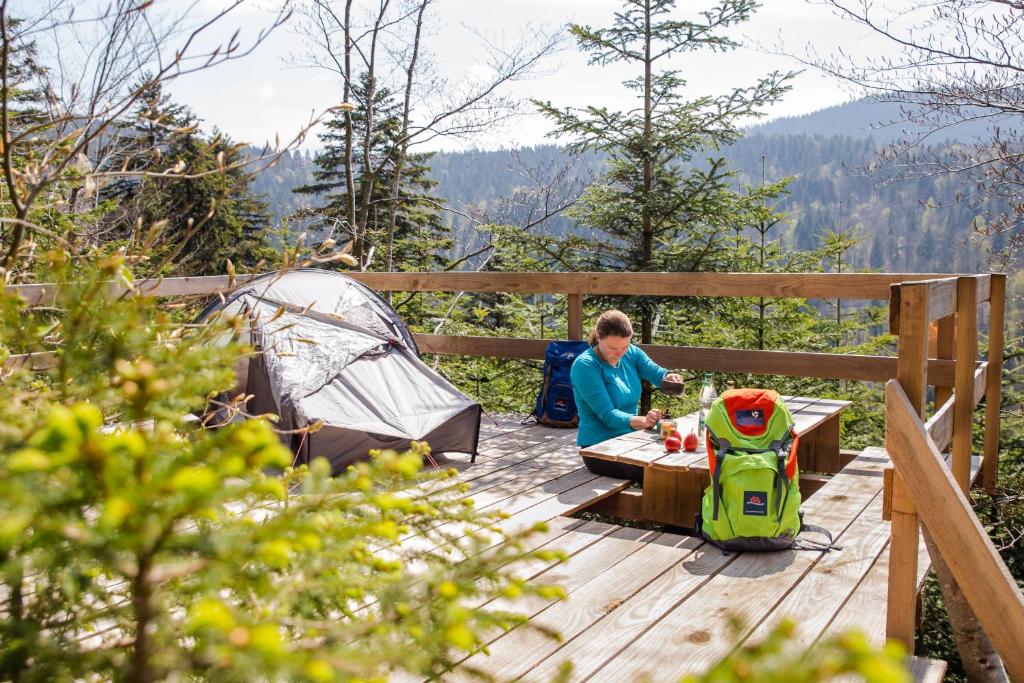 a woman sitting at a table next to a tent at TrekkingCamp Himmelsterrassen in Bad Peterstal-Griesbach