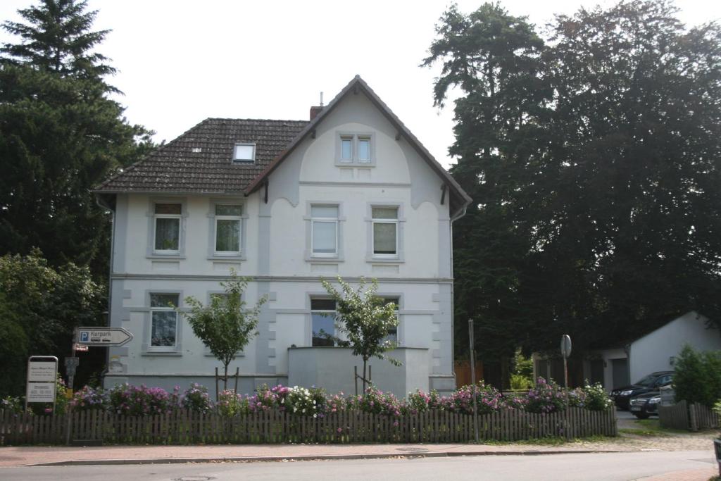 ein weißes Haus mit einem Zaun davor in der Unterkunft Ferienwohnung am Kurpark in Bad Nenndorf