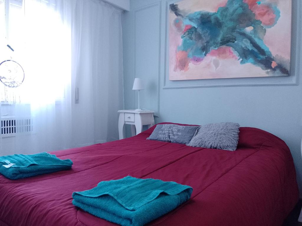 1 dormitorio con 1 cama roja y 2 toallas en Departamento en el Centro Histórico de Rosario en Rosario