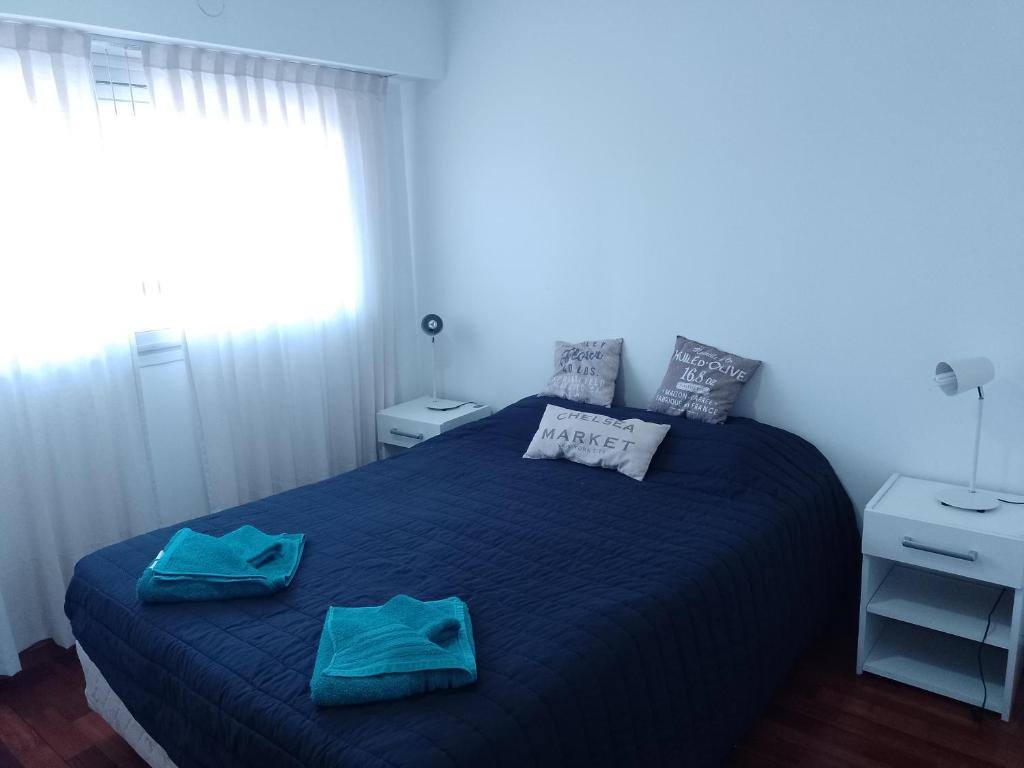 1 dormitorio con 1 cama azul y 2 toallas en Elegante Departamento en Barrio Martin en Rosario