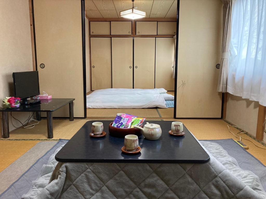 Una habitación con una mesa con tazas y una cama en 雲海と星空の宿 YAKUNO, en Fukuchiyama