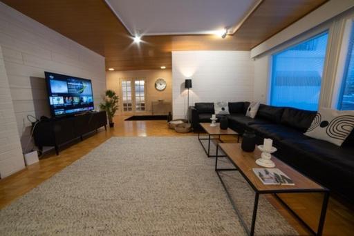 ein Wohnzimmer mit einem Sofa und einem TV in der Unterkunft Villa Mänty 200 m2 Korkeatasoinen kaupunkikoti in Seinäjoki