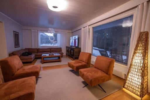 sala de estar con sofá, sillas y TV en Villa Närhi 230 m2 upea talo rauhallisella alueella en Seinäjoki