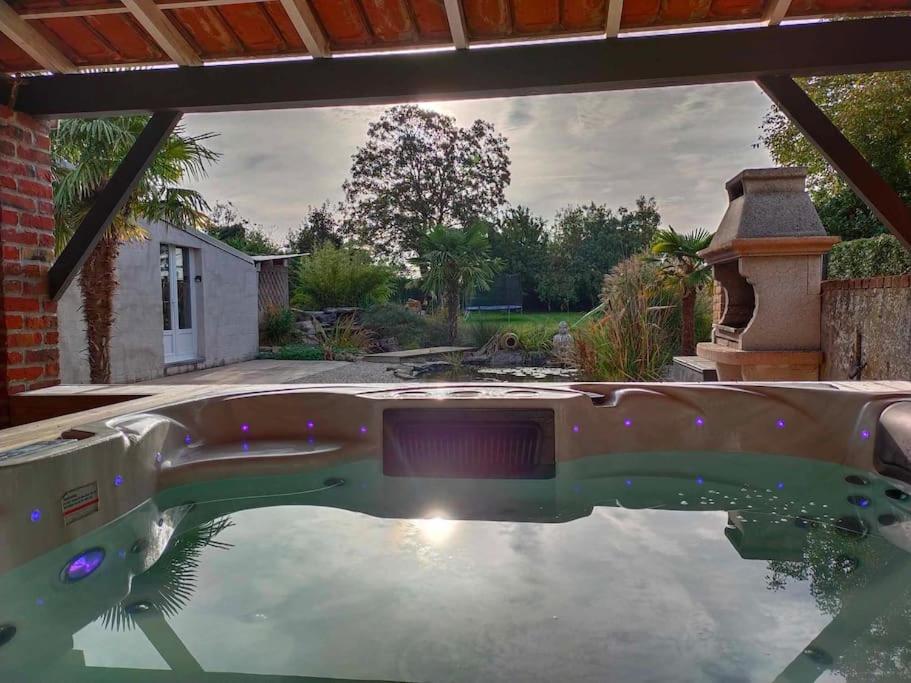 einen Pool im Hinterhof mit der Sonne im Wasser in der Unterkunft La maison aux escargots *Jacuzzi* in Hénin-Beaumont