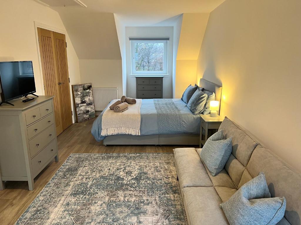 a bedroom with a bed and a couch and a television at Inchmurrin Townhouse, Loch Lomond in Bonhill