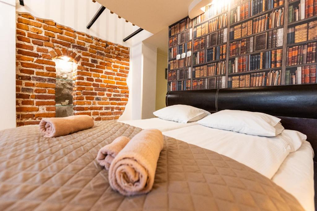 two beds in a bedroom with a brick wall at VINTAGE SENACKA APARTMENTS in Krakow