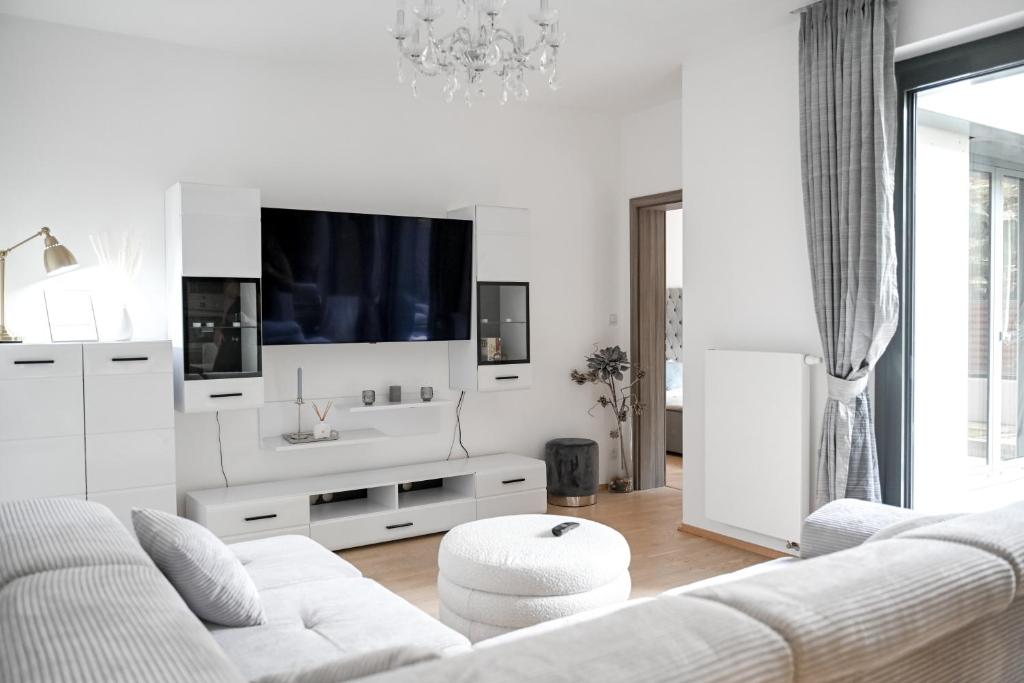 a white living room with a white couch and a tv at Lovely Family Suite in Prague