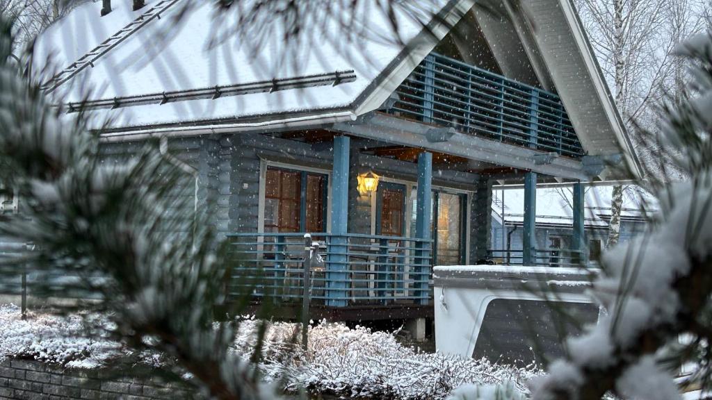 a house with a porch with snow on it at Villa Laakson Helmi 1 с камином, сауной, SPA, на берегу озера in Himos