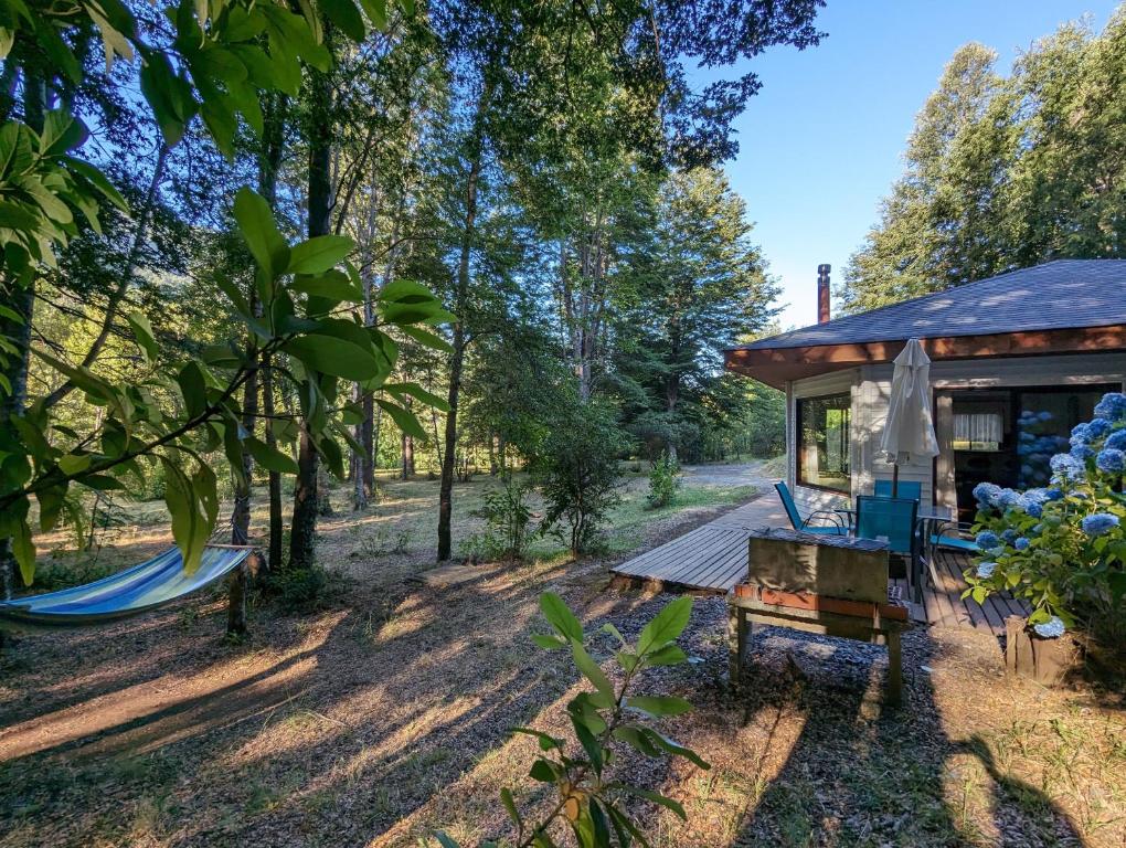 uma cabana na floresta com um deque e redes de descanso em Complejo Kari Mapu Park em Pucón