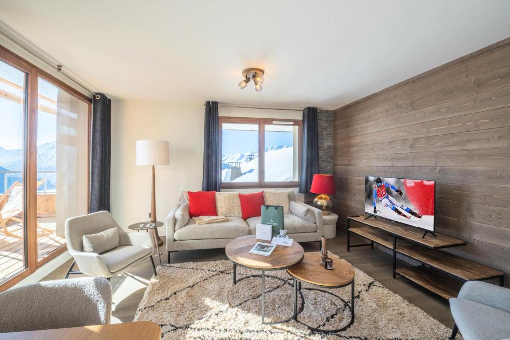 ein Wohnzimmer mit einem Sofa und einem TV in der Unterkunft Résidence Les Fermes De L'alpe - 3 Pièces pour 6 Personnes 584 in Huez