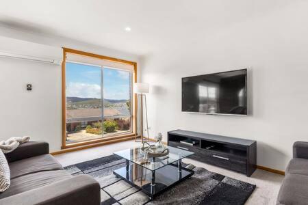 een woonkamer met een bank en een tv bij Lutana Large house in Hobart