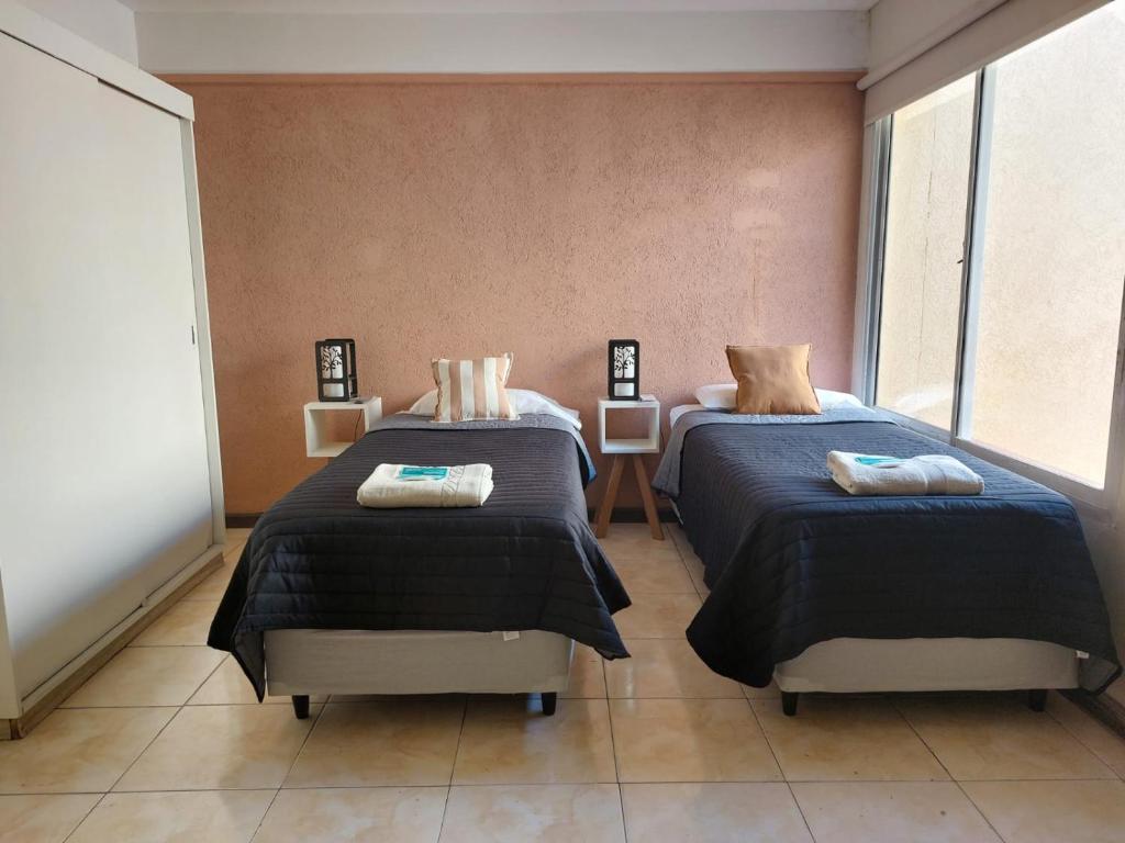 a bedroom with two beds and two windows at Apex Apart in Mendoza