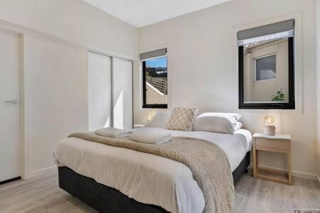 a white bedroom with two beds and a window at The View Studio Apartment Fully self-contained Sandy Bay in Sandy Bay