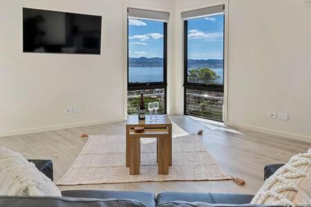 a living room with a table and large windows at The View Studio Apartment Fully self-contained Sandy Bay in Sandy Bay