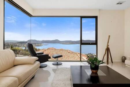 a living room with a couch and a large window at The View Sandy Bay 5 bedroom in Hobart