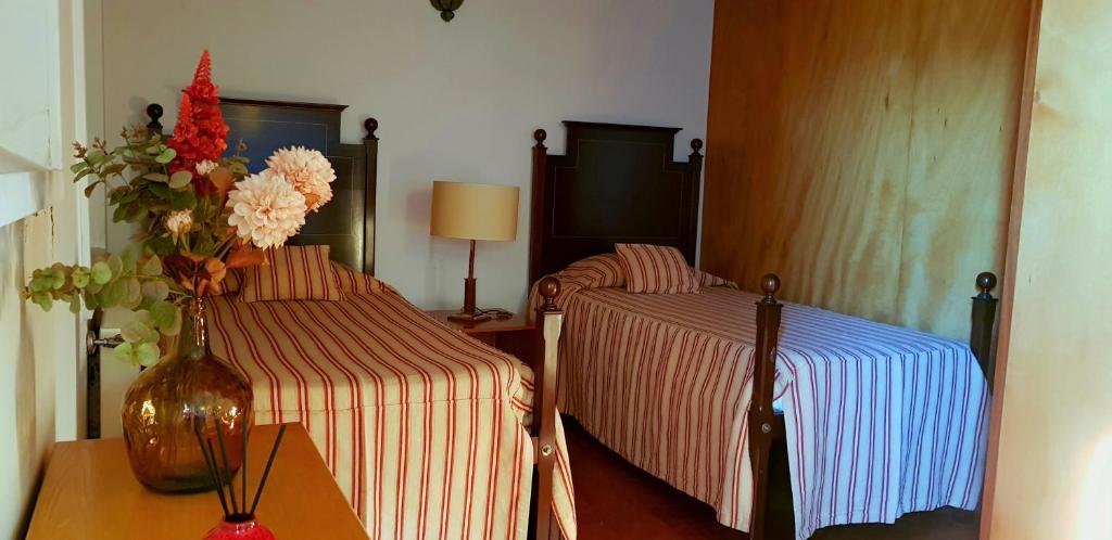 um quarto com duas camas e um vaso de flores sobre uma mesa em Palácio da Quinta da Portela II em Coimbra