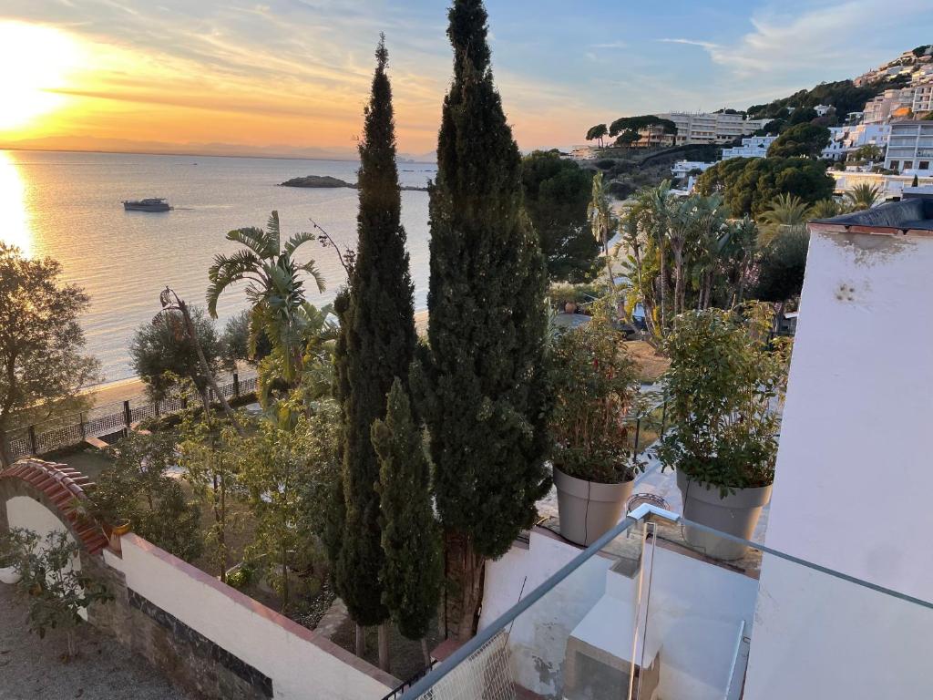 einen Balkon mit Bäumen und dem Meer bei Sonnenuntergang in der Unterkunft Veuràs el Mar - Madrague Beach apartment 15 in Roses