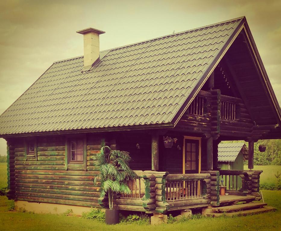 Cette grande maison en bois dispose d'une terrasse couverte et d'un toit. dans l'établissement Tirtsu puhkemaja, 