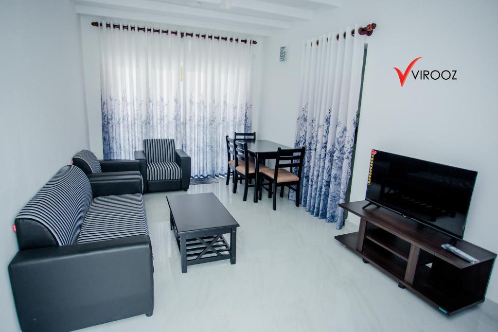 a living room with a couch and a tv and a table at Virooz Residence Rathmalana 2 Bedroom Apartment in Borupane